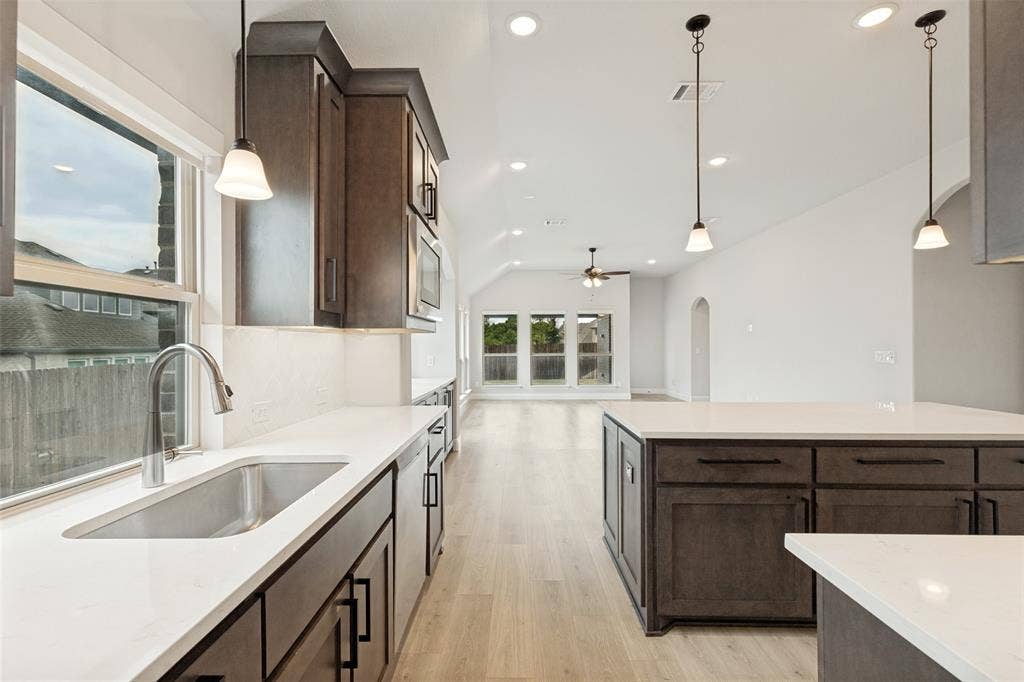 5405 Pooley Lane, McKinney, TX 75071 Kitchen featuring dark wood-finish cabinetry, white countertops, and a stainless steel sink with a gooseneck faucet