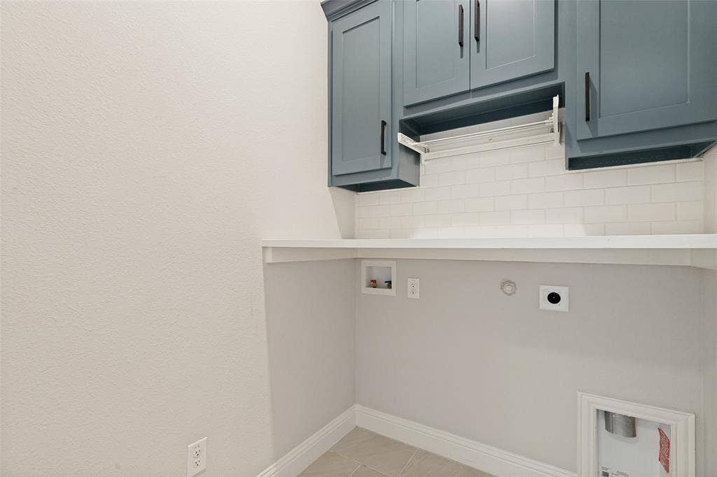 5405 Pooley Lane, McKinney, TX 75071 Utility space featuring blue shaker-style cabinetry with matte black hardware, a white subway tile backsplash, and a built-in drying rack
