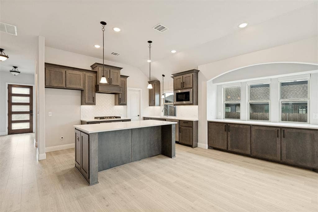 5405 Pooley Lane, McKinney, TX 75071 Expansive kitchen featuring a large central island with white countertop, recessed lighting, wood-finish flooring, and dark wood cabinetry