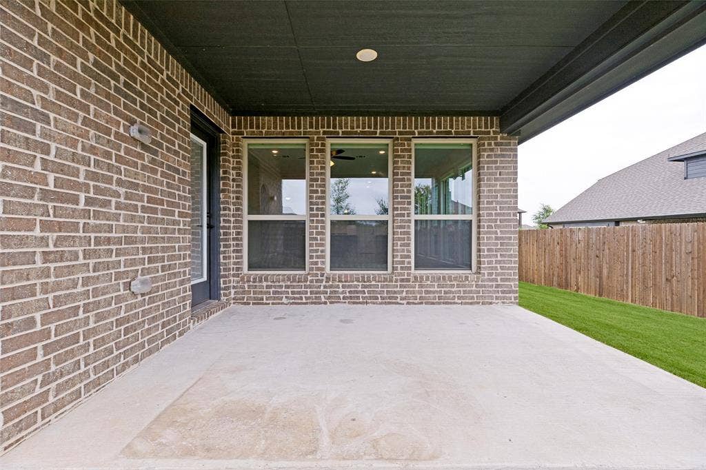 5405 Pooley Lane, McKinney, TX 75071 Covered concrete patio featuring a brick exterior, multiple windows, and a black exterior door