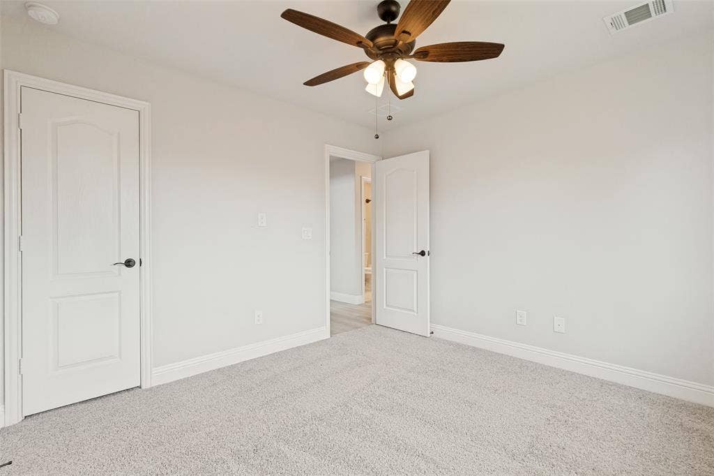 5405 Pooley Lane, McKinney, TX 75071 Neutral tone wall paint, light-colored carpeting, a dark wood-finish ceiling fan with integrated lighting, and white trim work