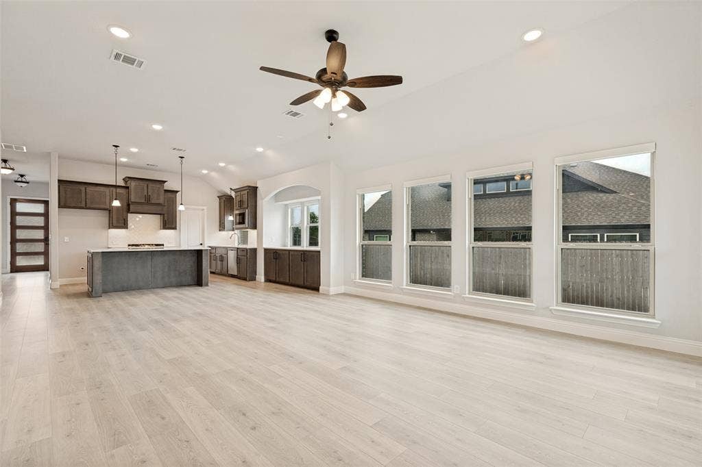 5405 Pooley Lane, McKinney, TX 75071 Bright open-concept living area featuring light wood-finish flooring, vaulted ceilings, and recessed lighting