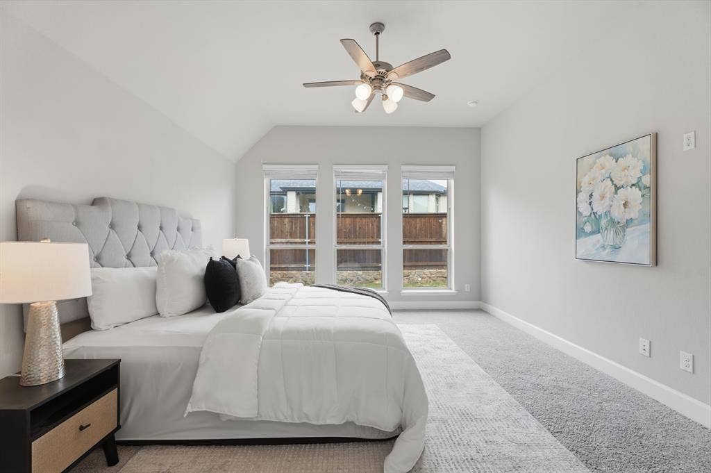 Bedroom featuring a vaulted ceiling with a ceiling fan, three horizontal windows with white blinds, and light gray carpet flooring