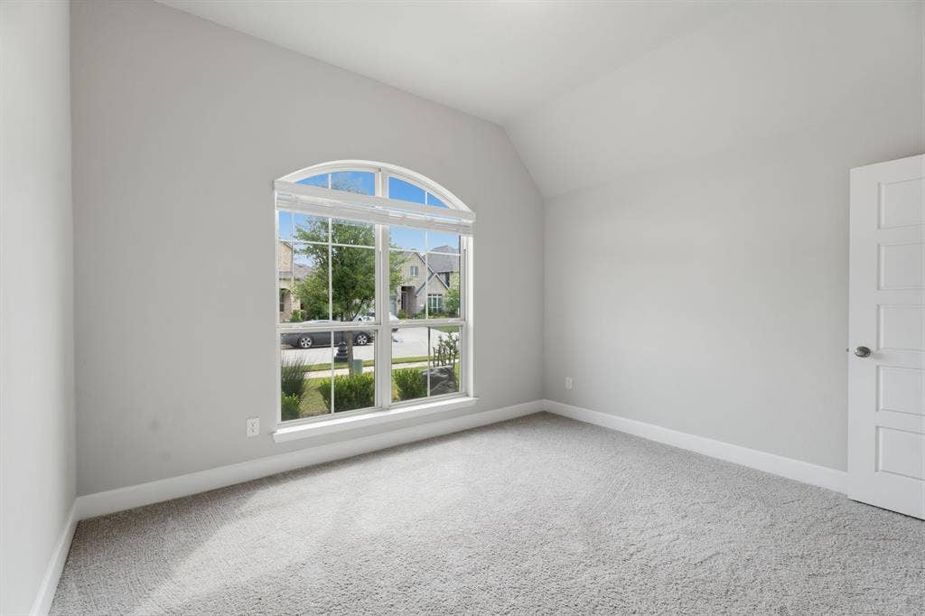 Room featuring a vaulted ceiling, light gray wall paint, and gray carpeting