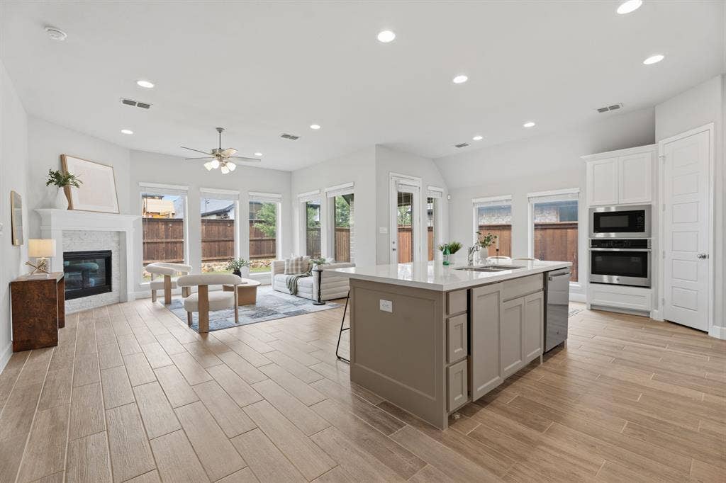 Open-concept living area with wood-finish flooring, recessed lighting, and ample natural light from multiple windows