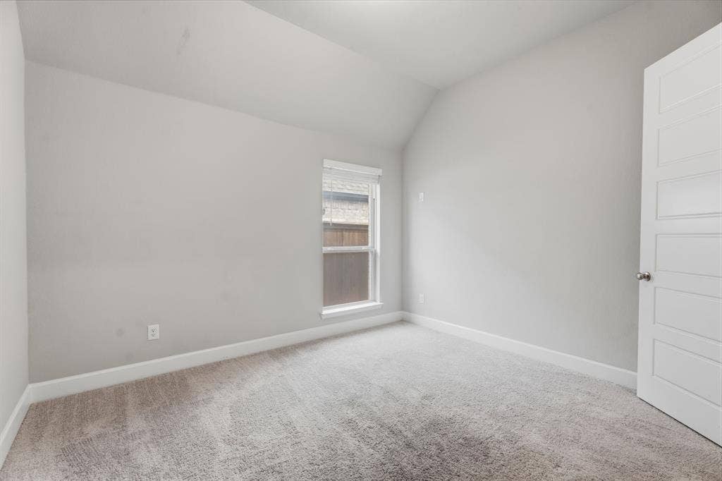 Carpeted room with a vaulted ceiling, light gray wall paint, and white baseboards