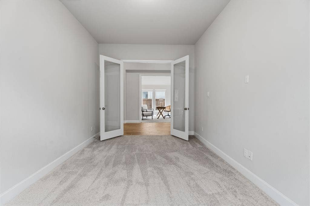 Light gray carpeted room with white trim and French doors