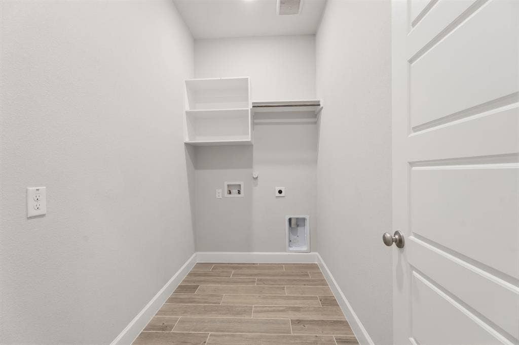 Dedicated laundry space featuring wood-finish tile flooring, recessed lighting, built-in shelving, and a hanging rod