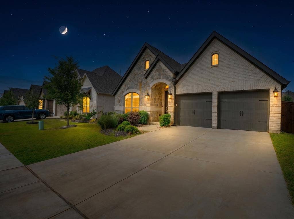Stone and brick exterior with a dual garage featuring arched lintels and carriage-style doors