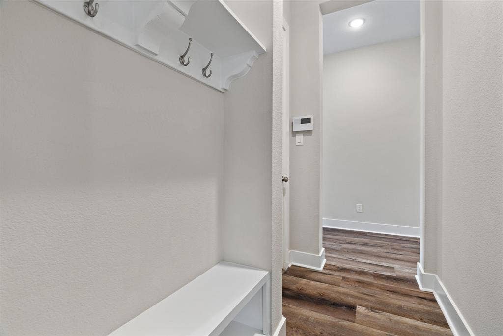 1821 Stonewall Road, Argyle, TX 76226 Built-in mudroom bench with shelving and coat hooks, complemented by wood-finish flooring and white baseboards