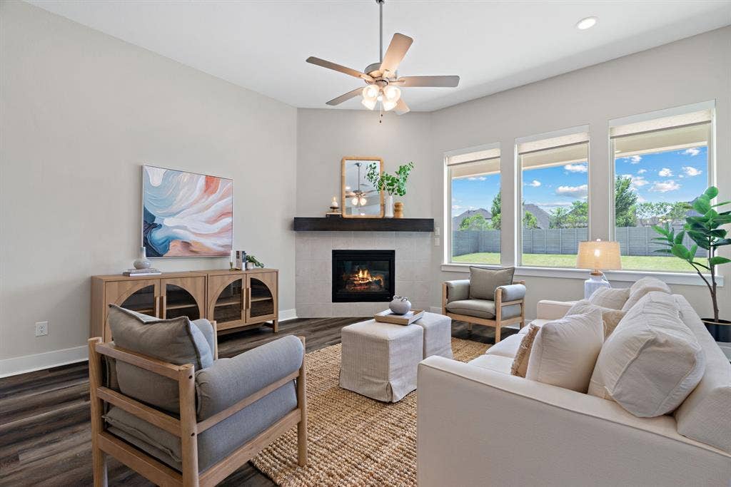 1821 Stonewall Road, Argyle, TX 76226 Living space featuring a corner fireplace with a dark wood mantel, wood-finish flooring, and a ceiling fan with integrated lighting