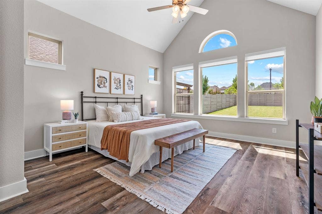 1821 Stonewall Road, Argyle, TX 76226 Vaulted ceiling with a ceiling fan and recessed lighting, wood-finish flooring, a wall of three picture windows, and an arched transom window