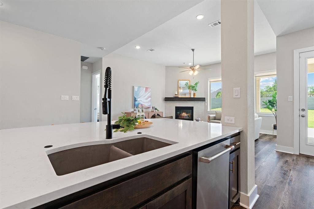 1821 Stonewall Road, Argyle, TX 76226 Kitchen island featuring a double basin sink with a matte black faucet, integrated dishwasher, and white solid surface countertop
