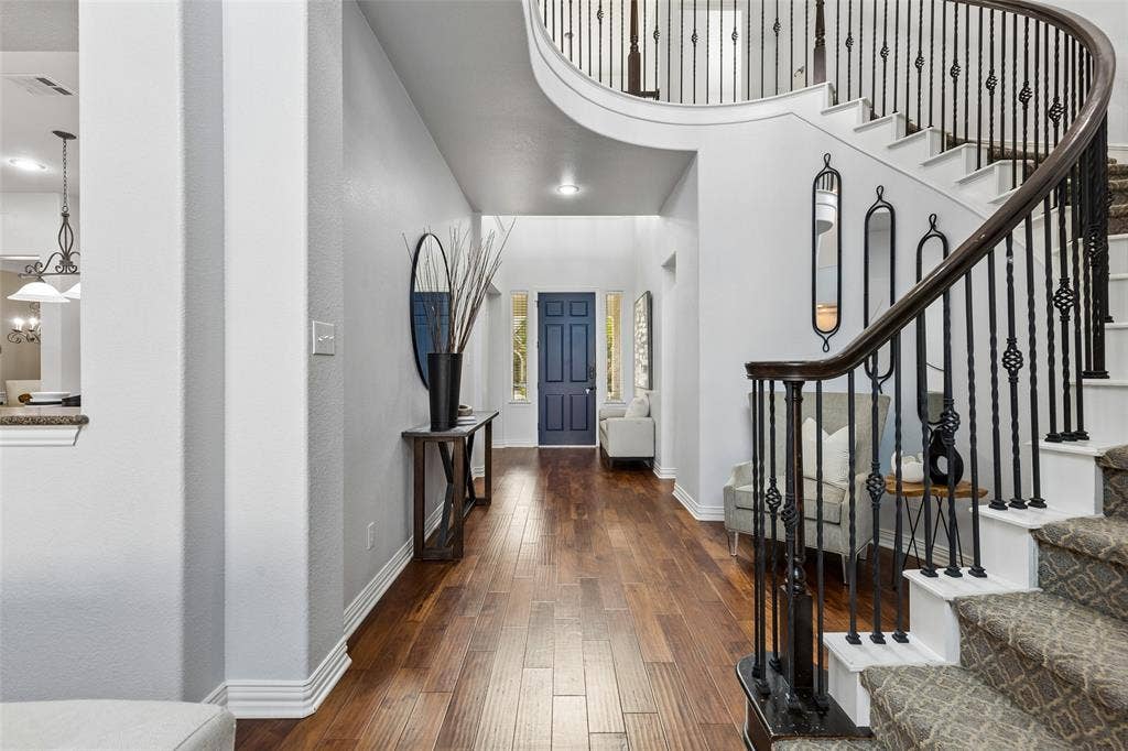 7975 Bishop Drive, Frisco, TX 75036 Grand foyer featuring engineered hardwood wood flooring and a curved staircase with wrought iron balusters