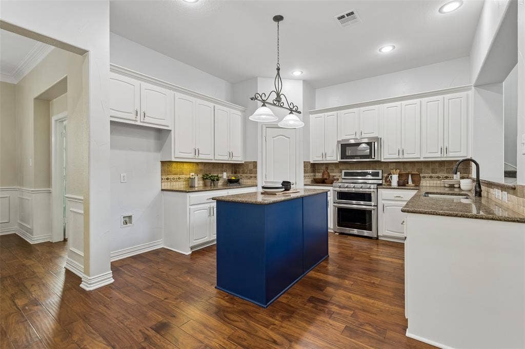 7975 Bishop Drive, Frisco, TX 75036 Kitchen featuring an island, granite countertops, white cabinetry, stainless steel appliances, engineered hardwood flooring, and walk in pantry.