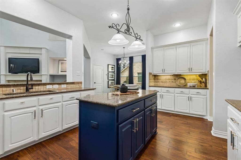 7975 Bishop Drive, Frisco, TX 75036 Kitchen featuring an island, granite countertops, white cabinetry, stainless steel appliances, engineered hardwood flooring, and walk in pantry.