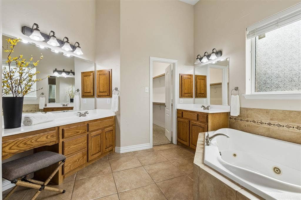 7975 Bishop Drive, Frisco, TX 75036 Spacious main level primary bathroom featuring split vanities, a built-in garden tub, separate shower, area to sit, private water closet and walk in closet.