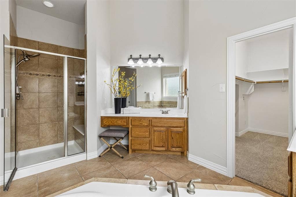 7975 Bishop Drive, Frisco, TX 75036 Spacious main level primary bathroom featuring split vanities, a built-in garden tub, separate shower, area to sit, private water closet and walk in closet.