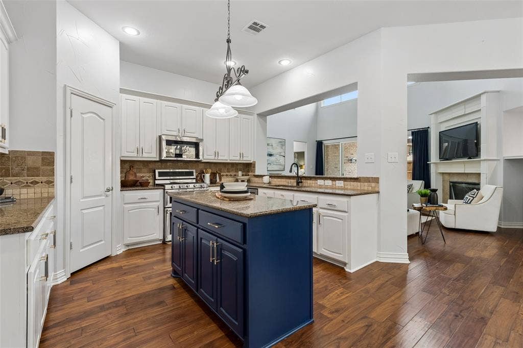7975 Bishop Drive, Frisco, TX 75036 Kitchen featuring an island, granite countertops, white cabinetry, stainless steel appliances, engineered hardwood flooring, and walk in pantry.
