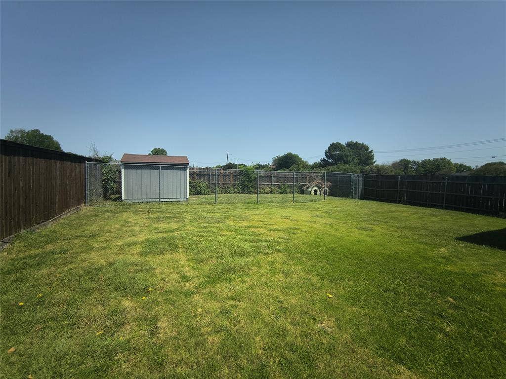3027 Ames Road, Lancaster, TX 75134 Expansive backyard featuring a lush lawn, a storage shed, and perimeter fencing