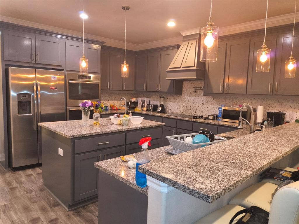 3027 Ames Road, Lancaster, TX 75134 Kitchen featuring dual islands, stainless steel appliances, grey cabinetry, granite countertops, and mosaic tile backsplash