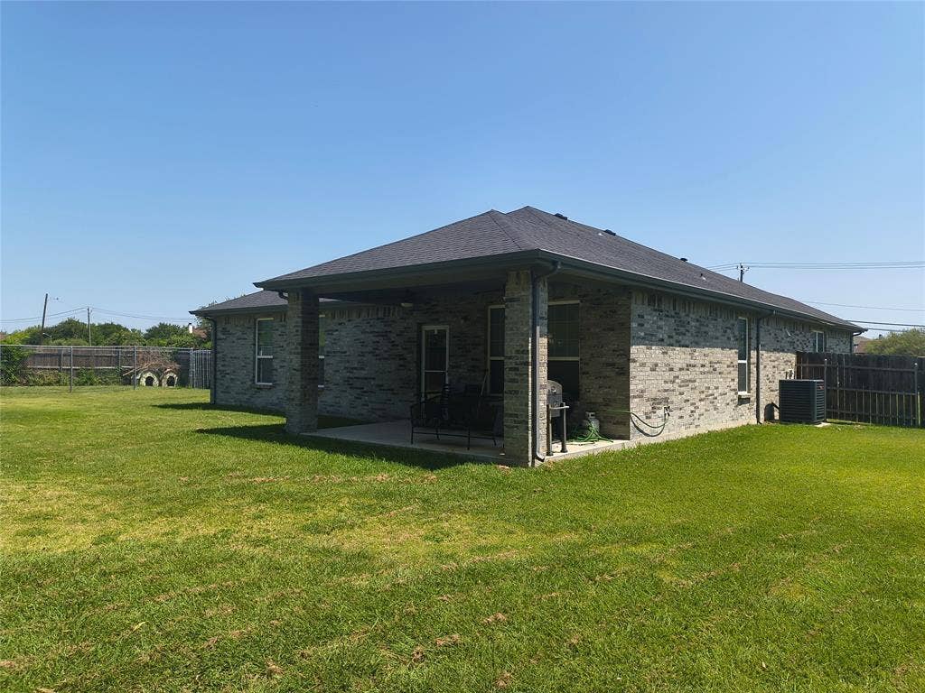 3027 Ames Road, Lancaster, TX 75134 Spacious backyard featuring a covered patio, brick exterior, dark shingle roof, and a wood privacy fence