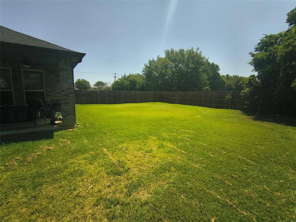 3027 Ames Road, Lancaster, TX 75134 Spacious backyard featuring a wood privacy fence and mature perimeter trees