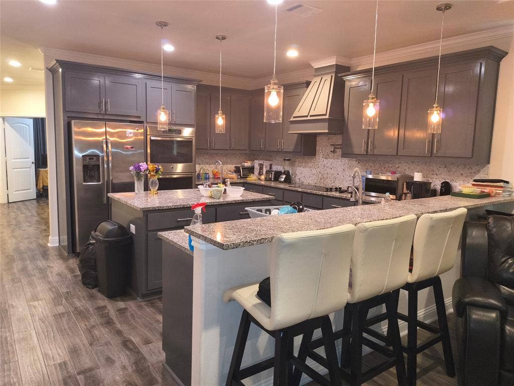 3027 Ames Road, Lancaster, TX 75134 Kitchen featuring grey cabinetry, stainless steel appliances, granite countertops, and wood-finish flooring