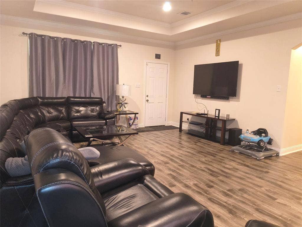 3027 Ames Road, Lancaster, TX 75134 Spacious living area featuring wood-finish flooring, a tray ceiling, and crown molding