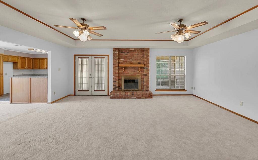600 Lyndon Drive, Woodway, TX 76712 Spacious living area featuring carpet flooring, a brick fireplace, tray ceiling detail, and French doors