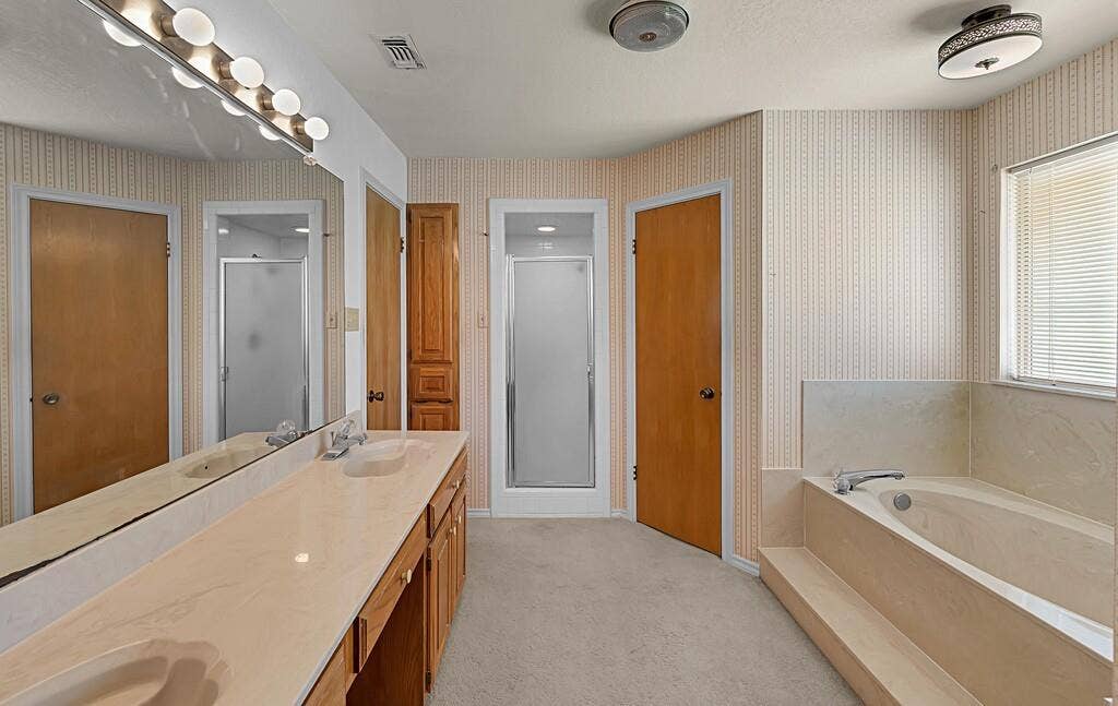 600 Lyndon Drive, Woodway, TX 76712 Bathroom featuring a dual vanity with a light-toned countertop, a built-in garden tub, and a separate shower enclosure