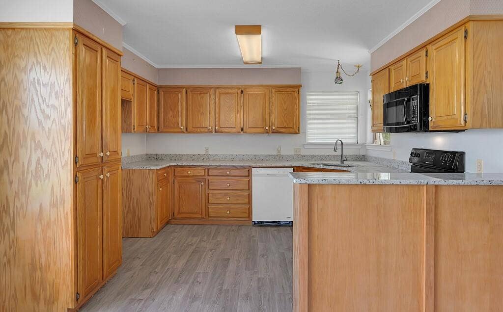 600 Lyndon Drive, Woodway, TX 76712 Kitchen featuring wood-finish cabinetry, granite-style countertops, an integrated sink with a gooseneck faucet, a built-in microwave, and wood-finish flooring