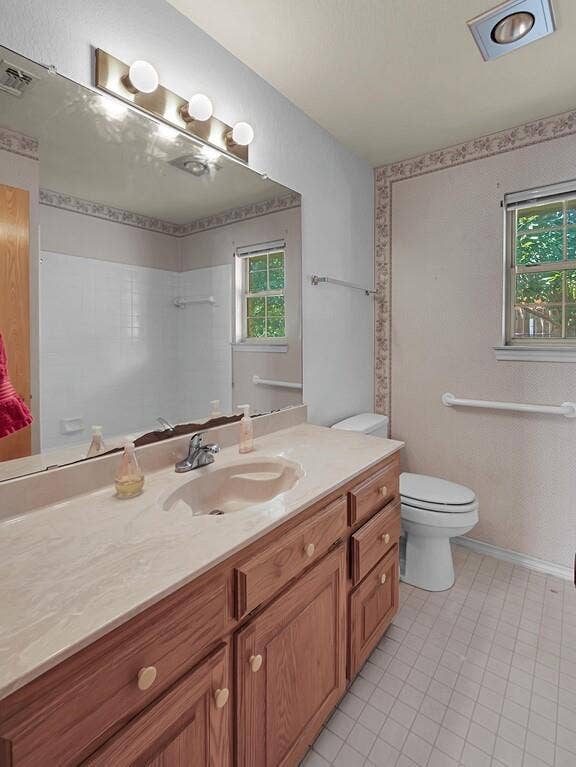 600 Lyndon Drive, Woodway, TX 76712 Bathroom vanity featuring a light-toned countertop with integrated sink, wood cabinetry, and a large mirror