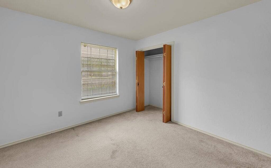 600 Lyndon Drive, Woodway, TX 76712 Carpeted room featuring a window with blinds, a bi-fold door closet, and a ceiling-mounted light fixture