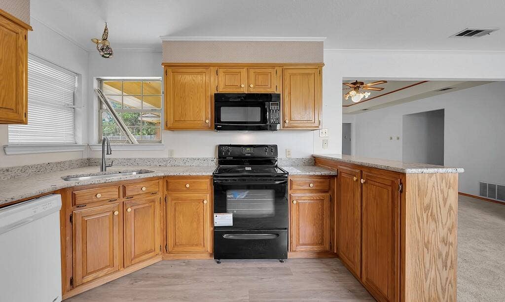 600 Lyndon Drive, Woodway, TX 76712 Kitchen featuring wood cabinetry, light-toned countertops, a stainless-steel sink, and black appliances