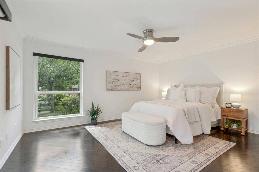 6362 Southpoint Drive, Dallas, TX 75248 Dark wood-finish flooring, white walls, large window with roller shade, ceiling fan with integrated lighting, and crown molding