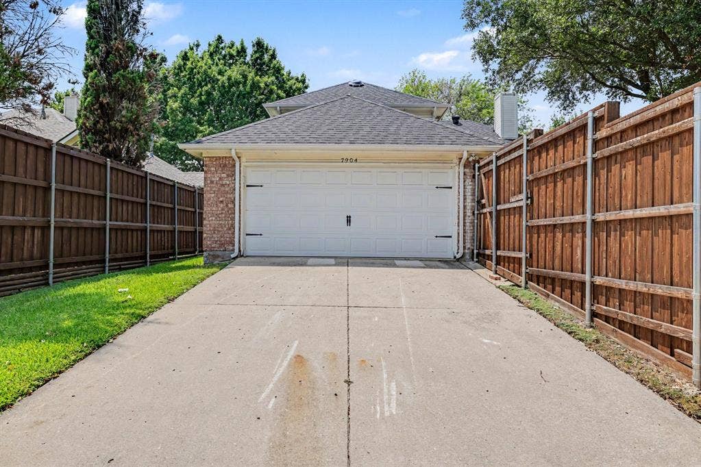 7904 Alderwood Place, Plano, TX 75025 Two-car garage with a white door and decorative hardware, brick facade, and a shingled roofline