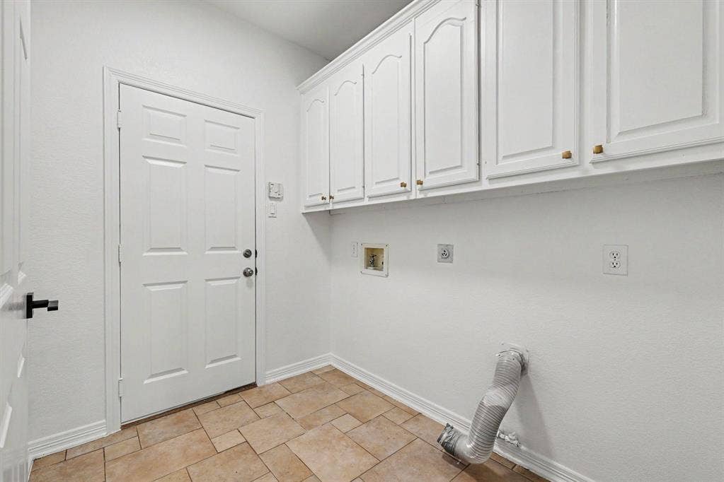7904 Alderwood Place, Plano, TX 75025 Utility area featuring upper cabinetry with gold-tone hardware, a paneled door, and neutral-toned tile flooring