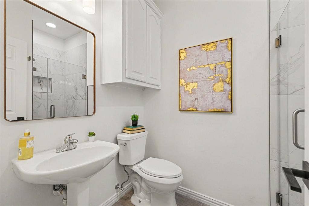 7904 Alderwood Place, Plano, TX 75025 Pedestal sink with chrome faucet, large framed mirror, and built-in white cabinetry