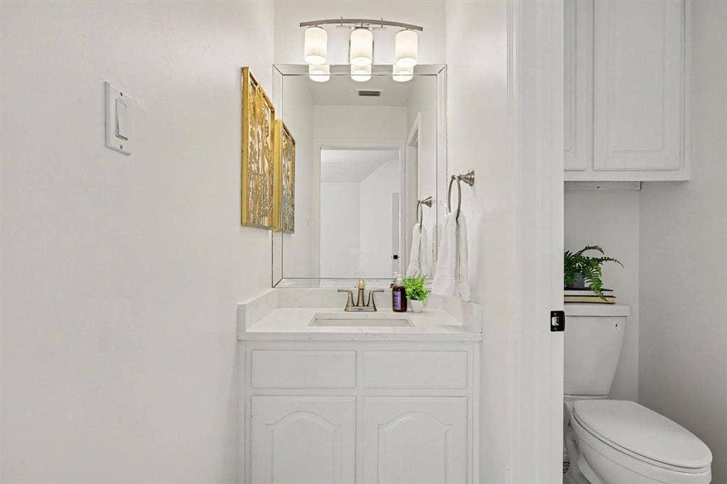 7904 Alderwood Place, Plano, TX 75025 Bright and functional bathroom featuring a white cabinetry vanity with dual drawers, integrated sink with brushed nickel faucet, and ample mirror with integrated lighting