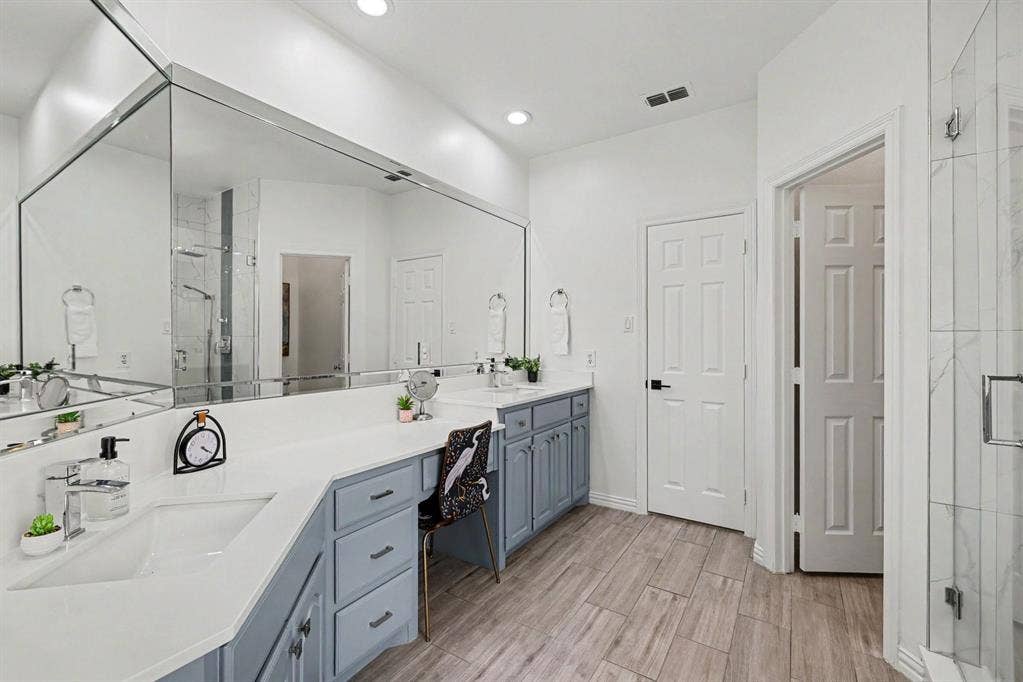 7904 Alderwood Place, Plano, TX 75025 Spacious bathroom featuring an expansive vanity with double undermount sinks, light blue cabinetry, and a countertop with integrated makeup desk