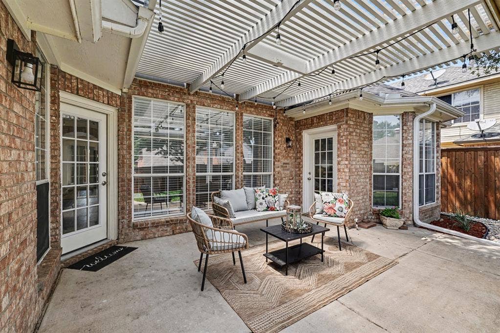 7904 Alderwood Place, Plano, TX 75025 Brick patio featuring a white slatted pergola, multiple large windows, a French-style door, and a concrete surface