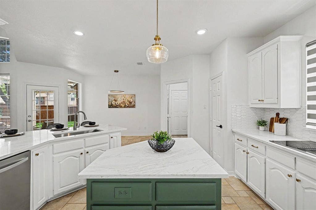 7904 Alderwood Place, Plano, TX 75025 Bright kitchen featuring a green-accented island with a white stone countertop, white cabinetry with gold-tone hardware, a stainless steel dishwasher, and a white hexagonal tile backsplash