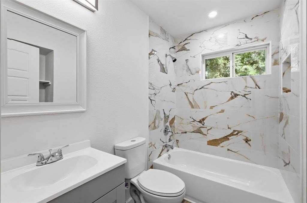 810 N Carrier Parkway, Grand Prairie, TX 75050 Bathroom featuring a single-basin vanity with a light gray cabinet, a framed mirror, and chrome fixtures