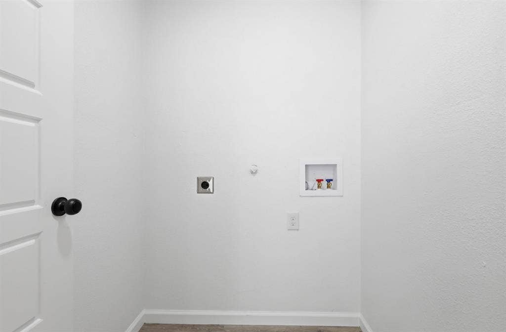 810 N Carrier Parkway, Grand Prairie, TX 75050 Dedicated utility area featuring white walls, baseboard trim, and a paneled door with a black knob