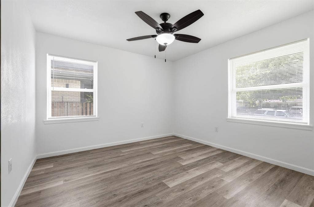 810 N Carrier Parkway, Grand Prairie, TX 75050 Room featuring wood-finish flooring, white walls, and a dark-toned ceiling fan with integrated lighting