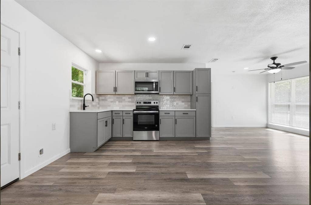 810 N Carrier Parkway, Grand Prairie, TX 75050 Modern kitchen featuring gray cabinetry, stainless steel appliances, and a white subway tile backsplash