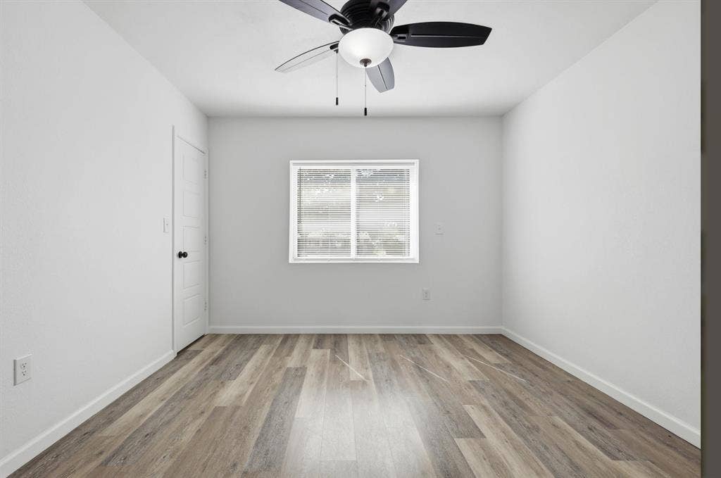 810 N Carrier Parkway, Grand Prairie, TX 75050 Bright room featuring wood-finish flooring, a contemporary ceiling fan with integrated lighting, a multi-pane window, and a white paneled door with black hardware