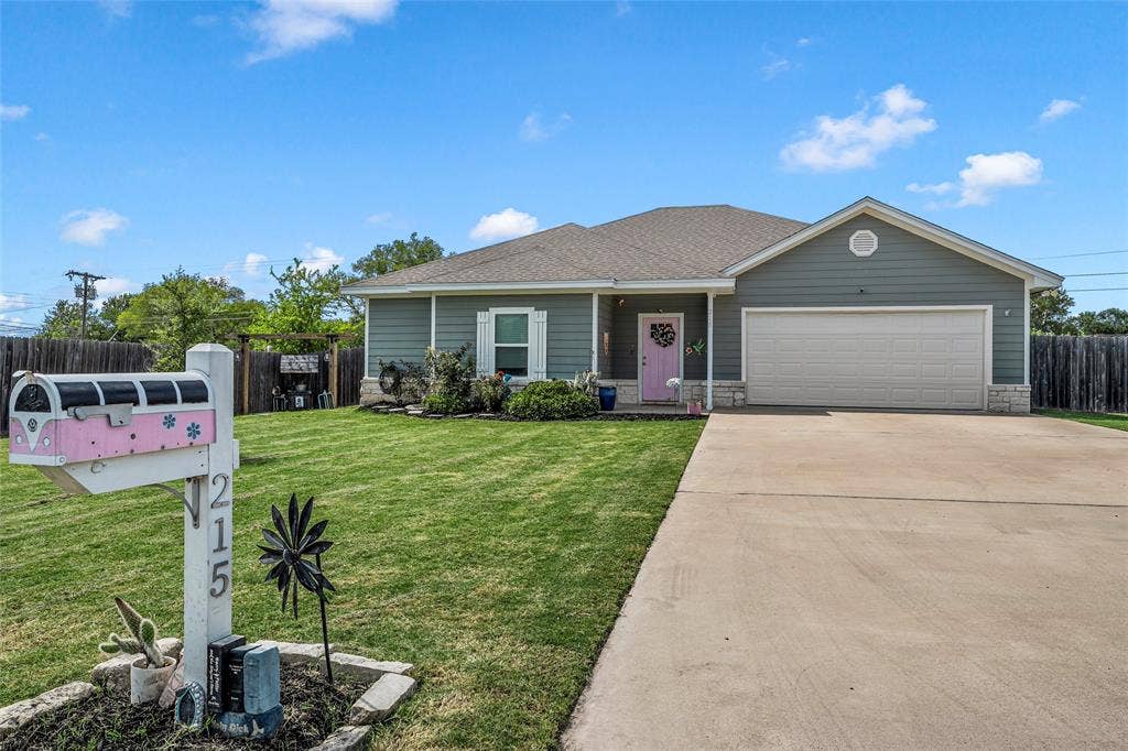 215 Greenbriar Street, Robinson, TX 76706 Single-story residence featuring a gray-green siding facade, a light-colored front door, and a two-car garage