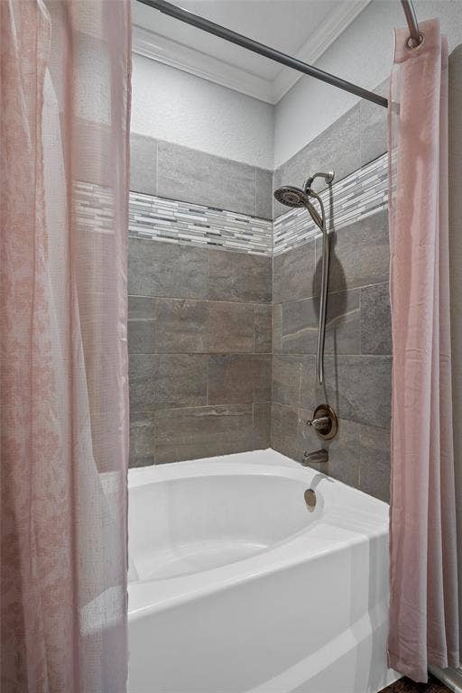 215 Greenbriar Street, Robinson, TX 76706 White drop-in tub with a wall-mounted shower system, complemented by gray tile surround with a decorative mosaic accent band